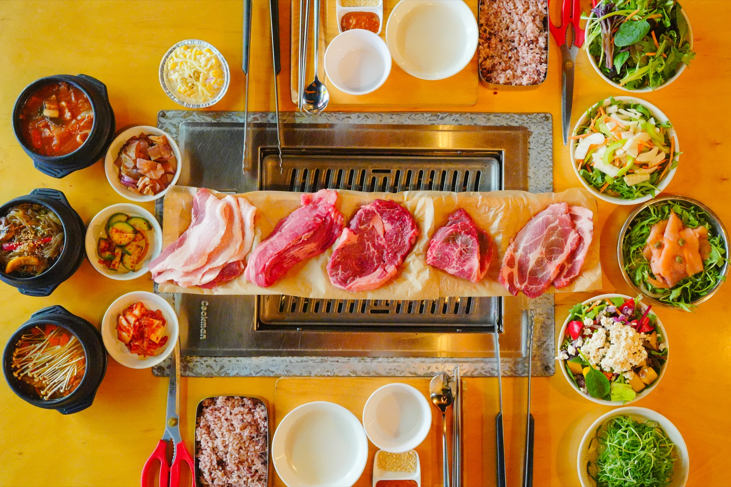 A full Korean BBQ table with meats ready for grilling